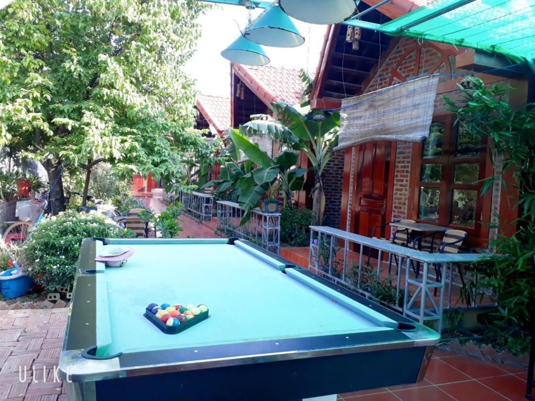 A pool table in an outdoor area with a brick building in the background.