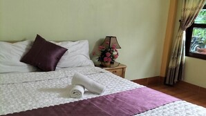 A neatly made bed with a white and purple bedspread, a rolled white towel, and a dark purple pillow. - Tam Coc Rice Fields Homestay (Nam Hoa Lu)