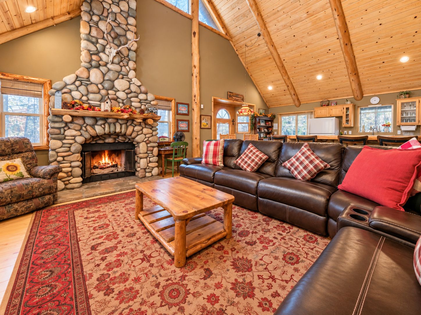 A cozy living room with a stone fireplace, leather sofa, and a wooden coffee table.