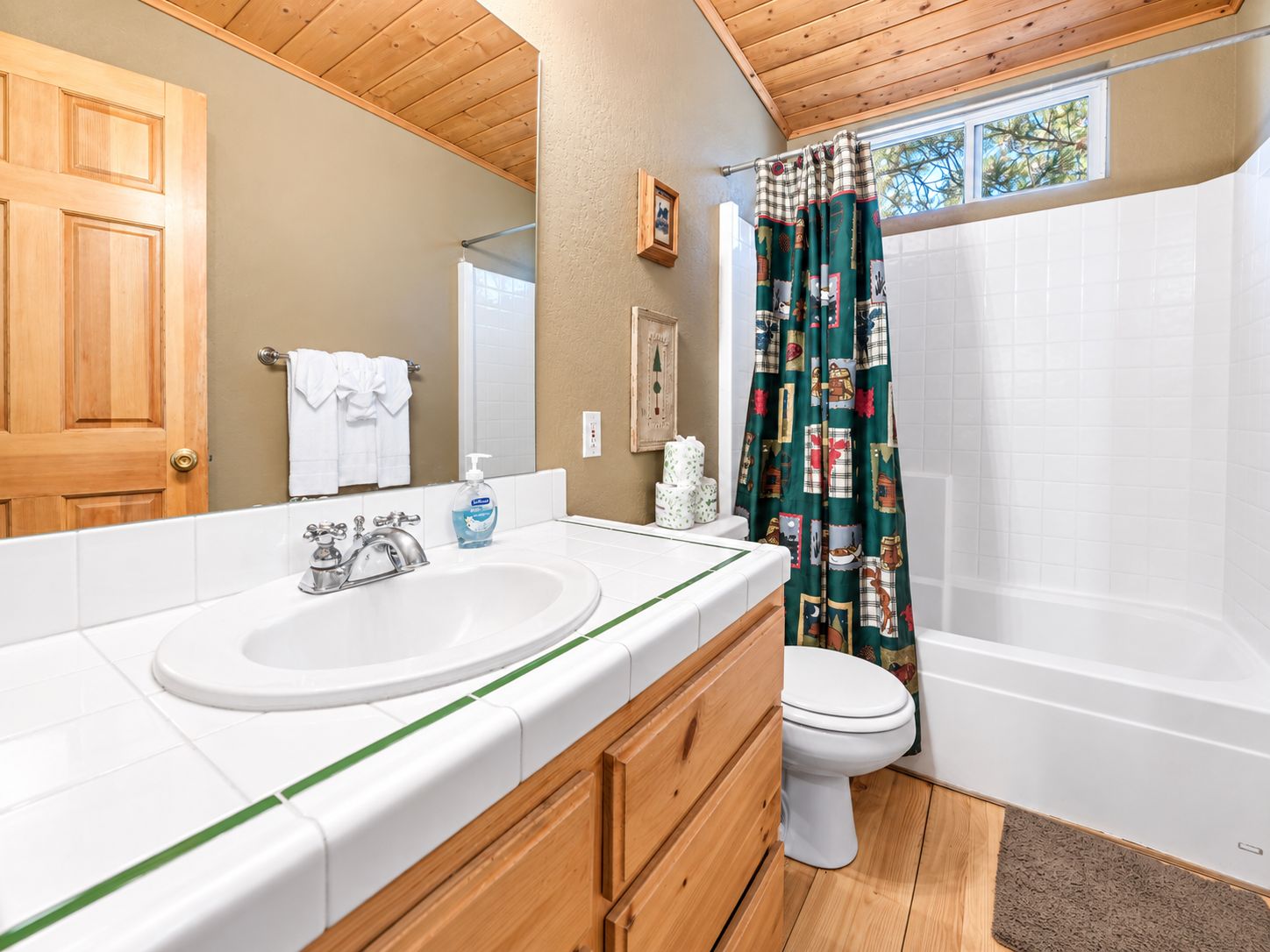 Un baño con tocador de madera, lavamanos, inodoro y cortina de ducha.