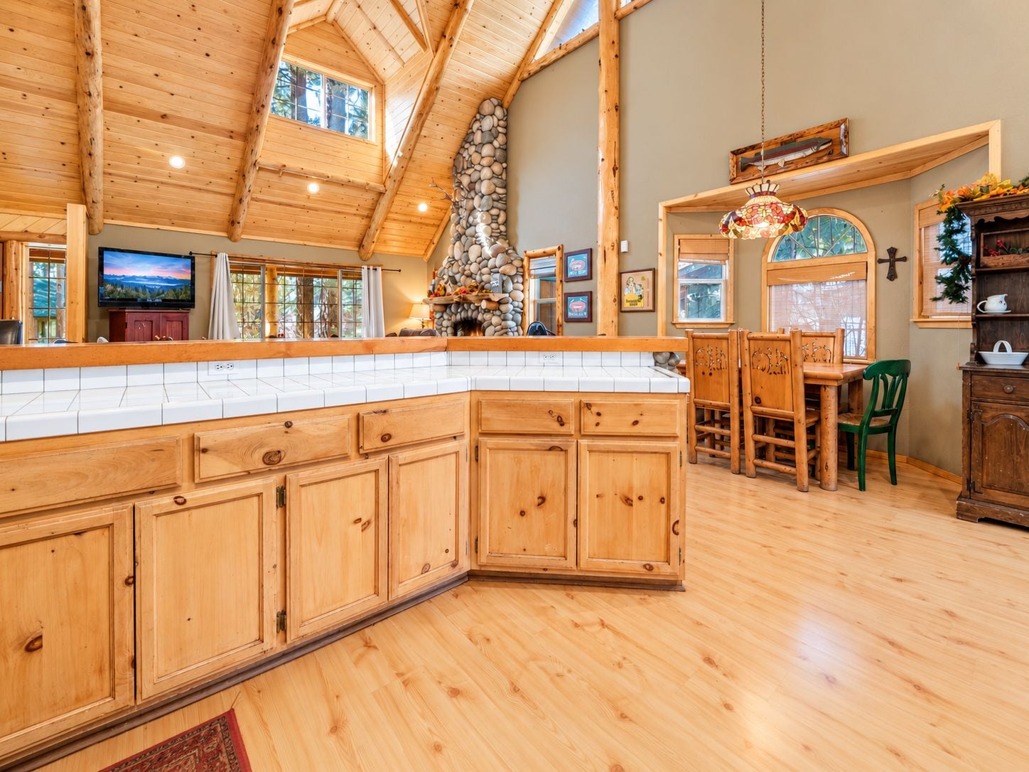 A spacious kitchen with wooden cabinets, a stone fireplace, and a dining area with a wooden table and chairs.