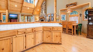 A spacious kitchen with wooden cabinets, a stone fireplace, and a dining area with a wooden table and chairs.