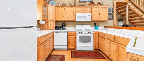 A kitchen with wooden cabinets, a microwave, a stove, and a refrigerator.