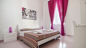 A bedroom with a bed, a nightstand, a lamp, a window with curtains, and a wall art piece. - Speciale Guesthouse (Rome)