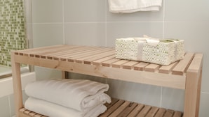 A wooden bench with a woven basket and folded towels in a bathroom. - Speciale Guesthouse (Rome)