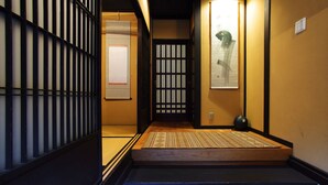 A traditional Japanese interior with tatami flooring, a sliding door, and a small decorative stone. - Kyo Akari Inn (Kyoto)