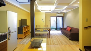 A modern living room with a dining area, a sofa, and a television. - Kyo Akari Inn (Kyoto)