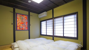 A room with a bed, a large window with a view, and an air conditioner on the wall. - Kyo Akari Inn (Kyoto)