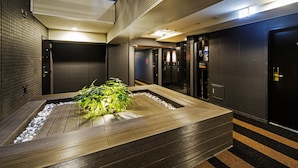Espaço moderno de elevador com um banco de madeira e uma pequena planta.