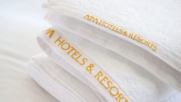 Una pila di asciugamani bianchi con ricamo che riporta la scritta “AAA HOTELS & RESORTS”.