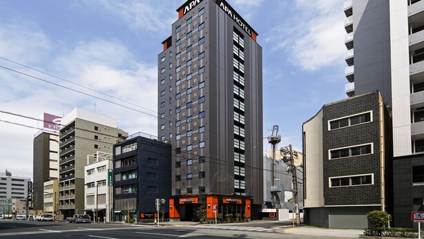Um hotel moderno com uma placa chamativa, vários andares e um estacionamento em frente.