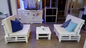 Dos sofás blancos con almohadones azules y azul claro, una mesita blanca con un adorno y un mueble blanco con cajones y una decoración de estrella.
