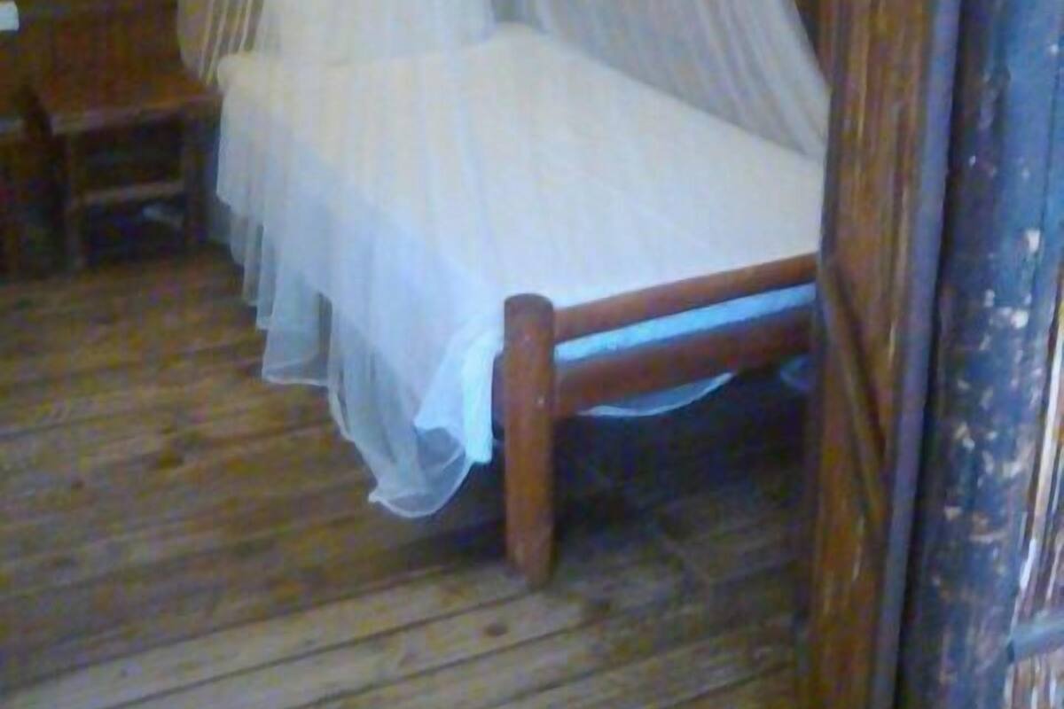 Quarto de madeira com cama sob um dossel.