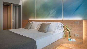 Ein modernes Hotelzimmer mit einem ordentlich bezogenen Bett, einem Nachttisch mit einem Buch und einer Blumenvase sowie einem großen Fenster mit Blick auf die Stadt.