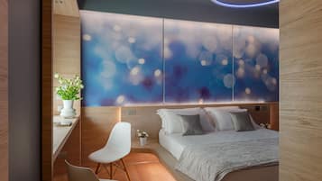A modern bedroom with a large bed, a desk, and a chair.