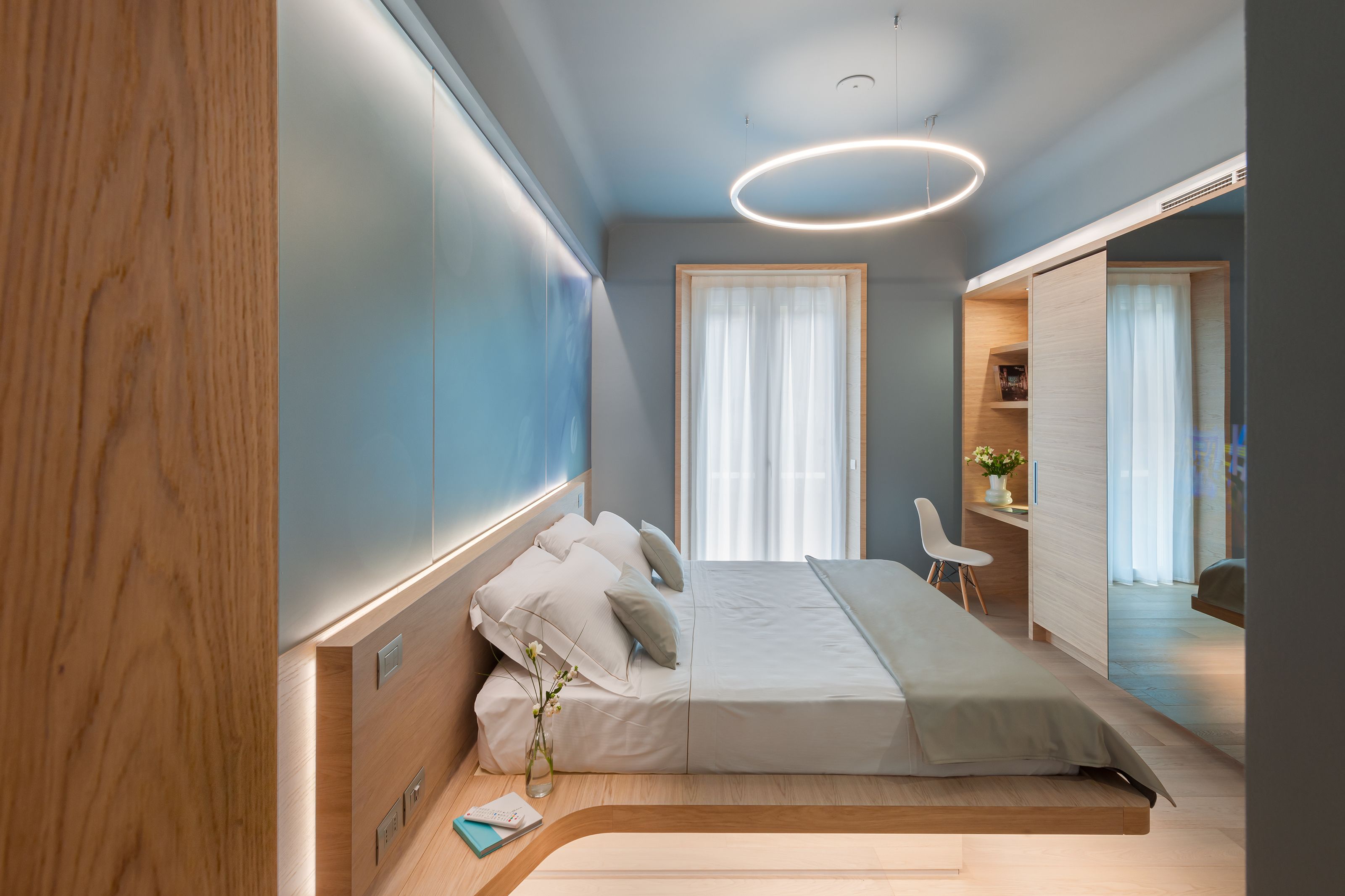 A modern bedroom with a bed, bedside table, and a desk area.