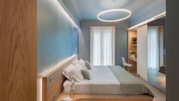 A modern bedroom with a bed, bedside table, and a desk area.