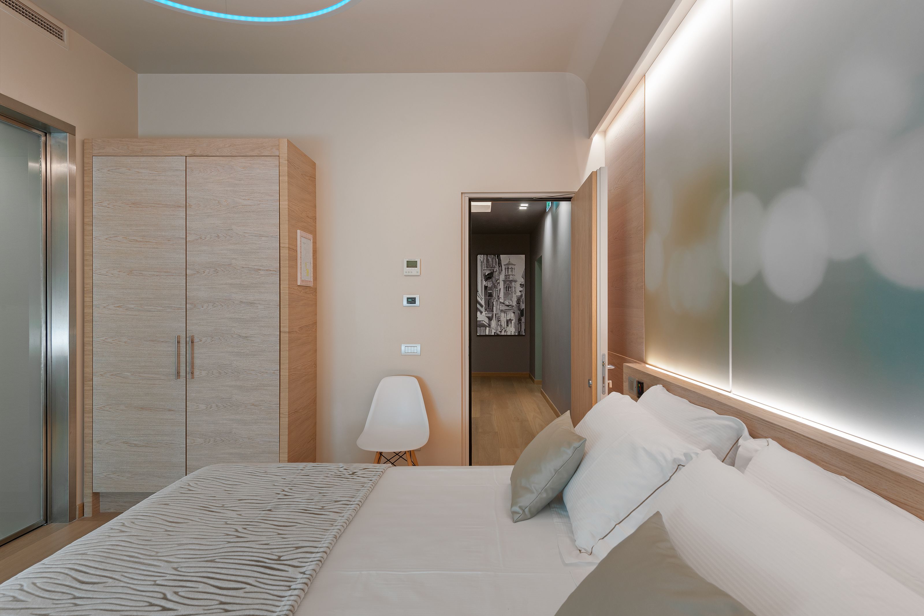 Camera da letto moderna con un letto grande, un armadio e un tavolino con una lampada.