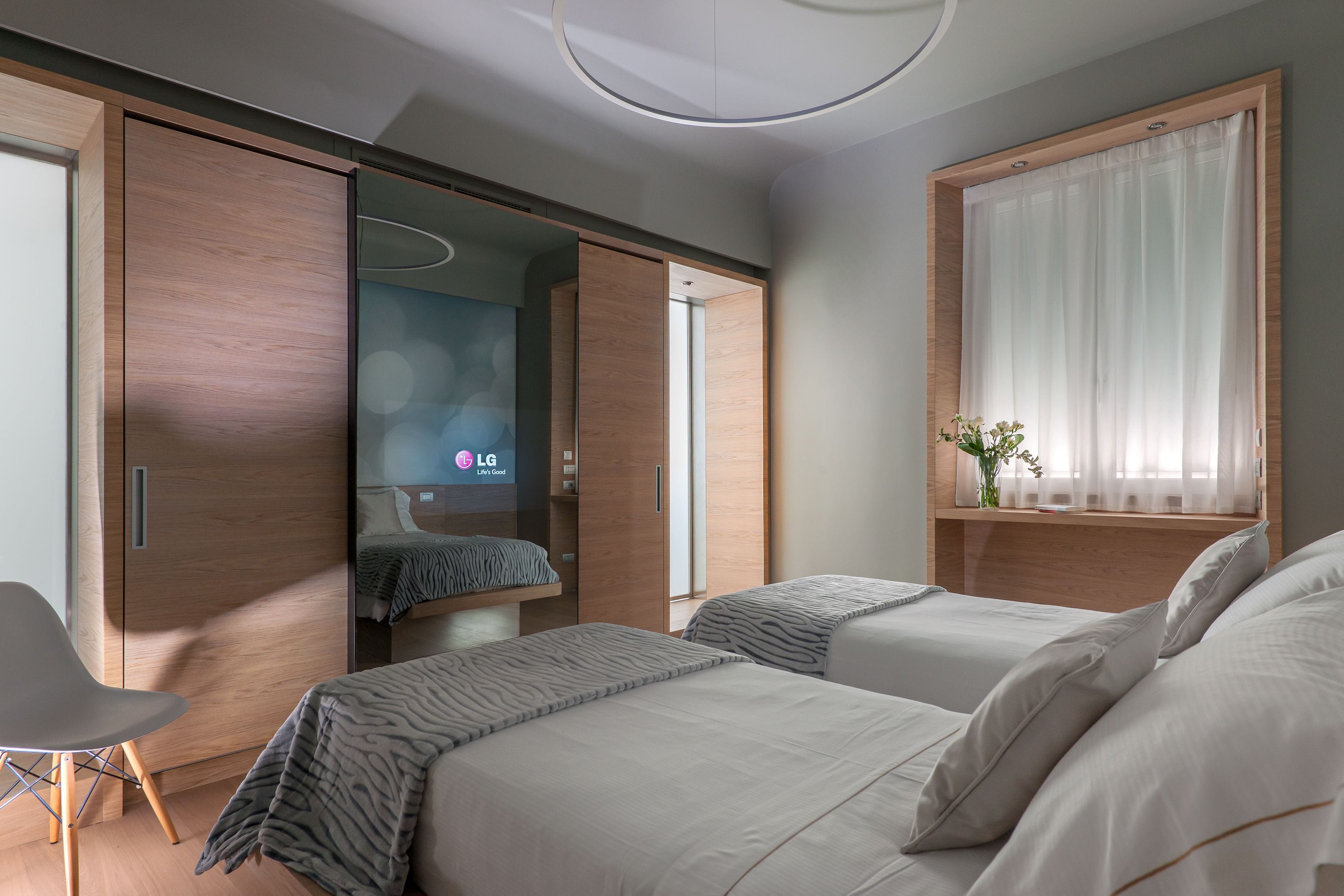 Ein modernes Hotelzimmer mit zwei Betten, einer Sitzecke und einem großen Spiegel.