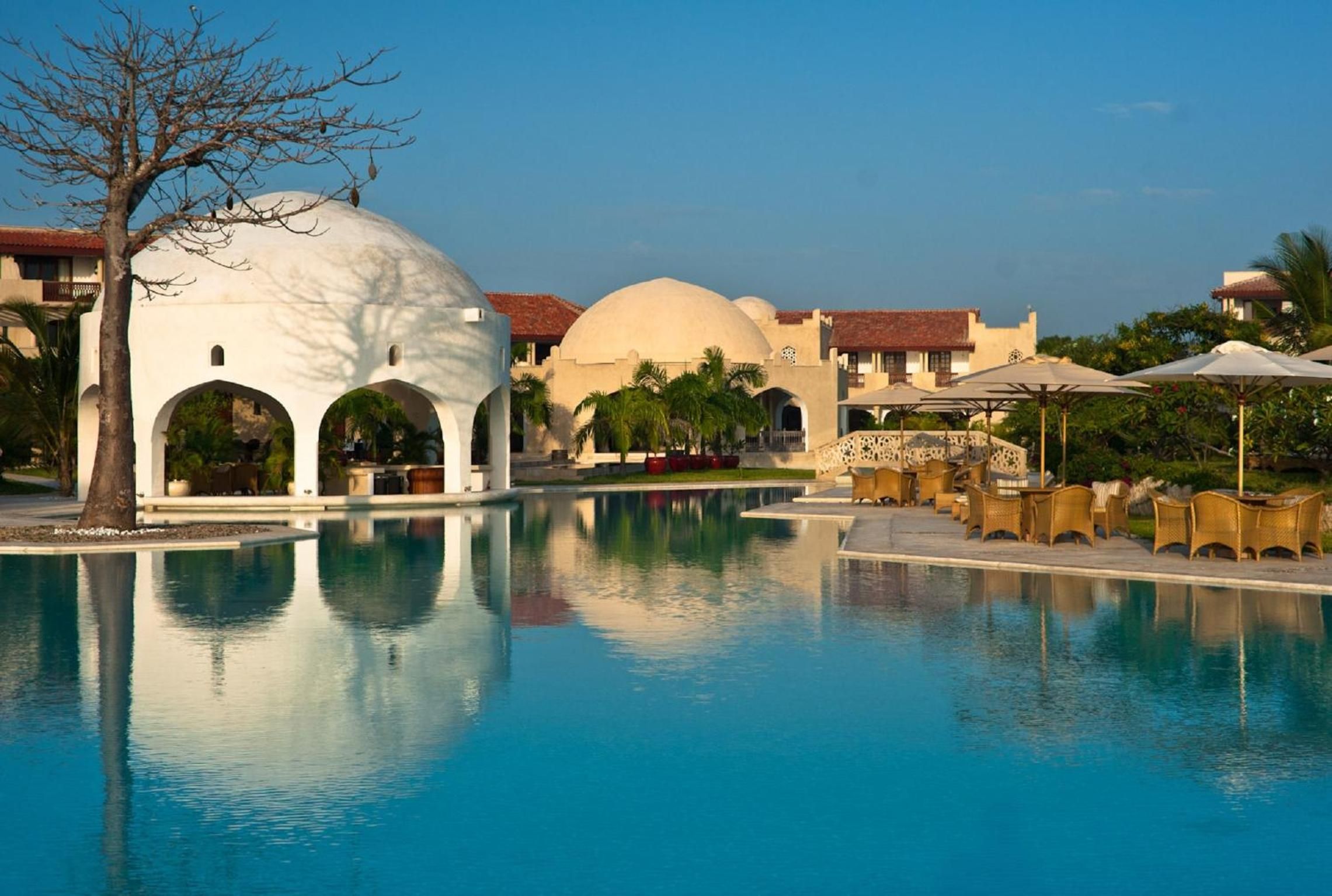 A resort with a large pool, white domed structures, and palm trees.