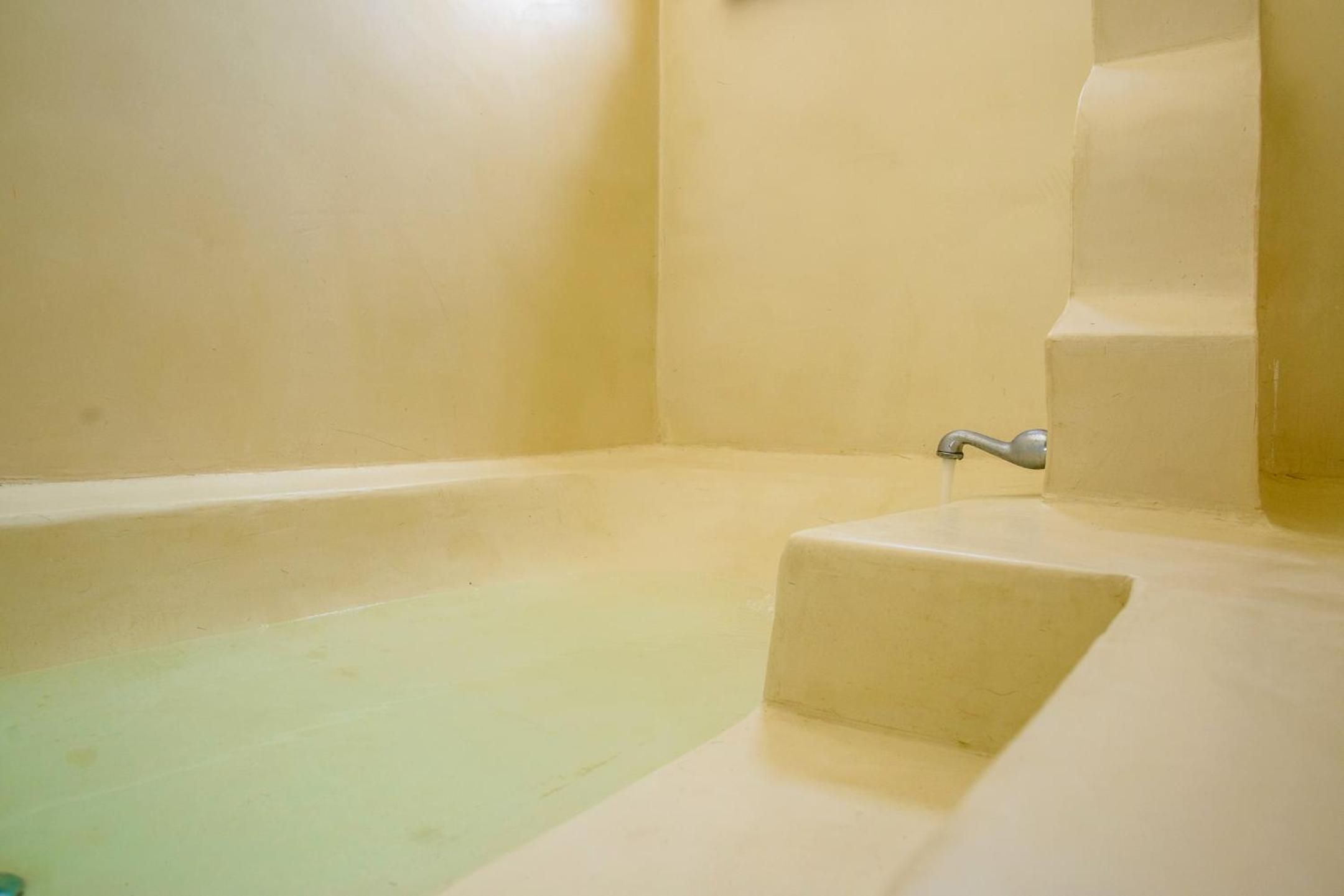 A bathtub with a faucet and steps leading into it.