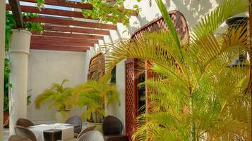A patio area with wicker furniture, a table set for dining, and a potted plant.