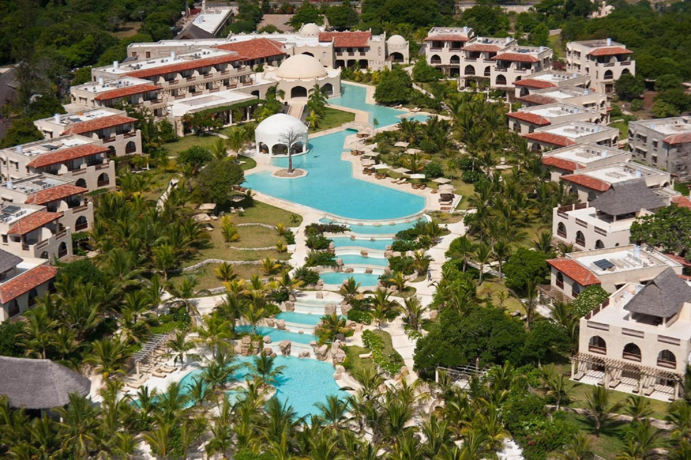 Ein Resort mit mehreren Swimmingpools, Palmen und mediterranem Baustil.