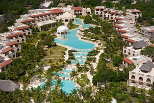 Ein Resort mit mehreren Swimmingpools, Palmen und mediterranem Baustil.