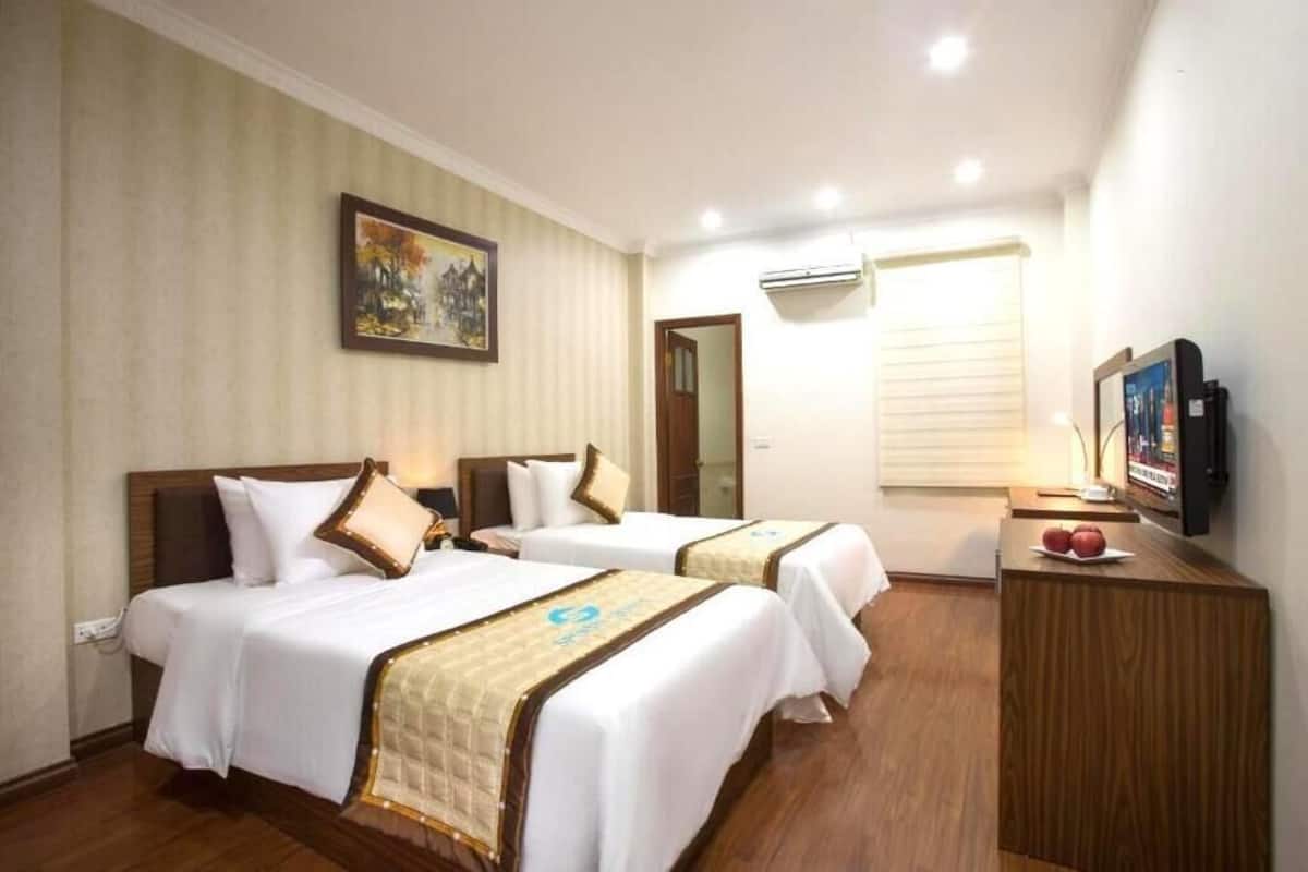 A hotel room with two beds, a TV, and an air conditioning unit.