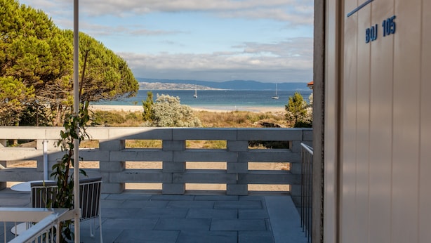 Ein Balkon mit Blick auf das Meer, einen Strand und eine entfernte Skyline.