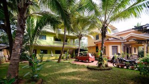 A two-story building with a balcony, surrounded by palm trees and a lawn. - Sunshine Park Homes (Colva)
