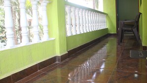 A corridor with a green wall, white balustrade, and a chair. - Sunshine Park Homes (Colva)