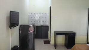 A compact kitchen with a refrigerator, a sink, and a small table. - Sunshine Park Homes (Colva)