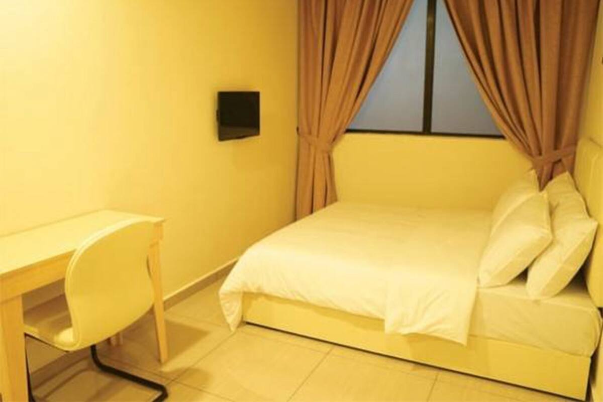 A room with a bed, a desk, and a window with curtains.