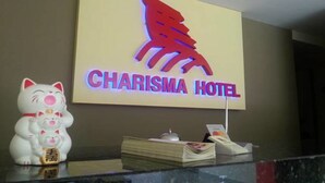 A Charisma Hotel sign with a red logo and a Maneki-neko figurine on the counter. - Charisma Hotel (Kuala Lumpur)