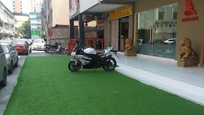 A building with a green artificial lawn, a parked motorcycle, and a lion statue. - Charisma Hotel (Kuala Lumpur)