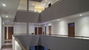 A multi-level interior with a central open space, railings, and doors leading to different areas. - Charisma Hotel (Kuala Lumpur)