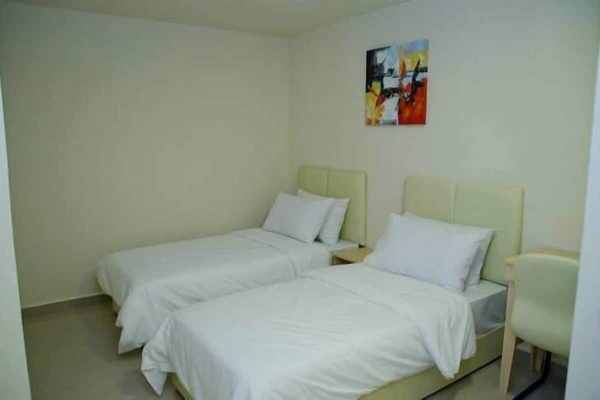 A room with two single beds, each with a nightstand and a chair.