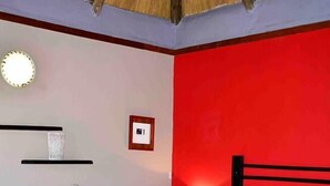 A bedroom with a bed, a nightstand, a wall-mounted shelf, and a ceiling fan.