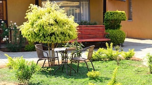 A patio with a table and chairs, a red bench, and a thatched roof structure.