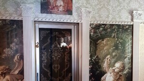 A room with a grand fireplace, ornate wall decorations, and a red chair. - Villa Jean Em (Netanya)