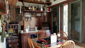 A cozy dining area with a wooden table and chairs, surrounded by shelves with various bottles and kitchenware. - Villa Jean Em (Netanya)