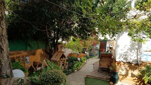 A garden with a wooden playhouse, a small wooden bridge, and a variety of plants and trees. - Villa Jean Em (Netanya)
