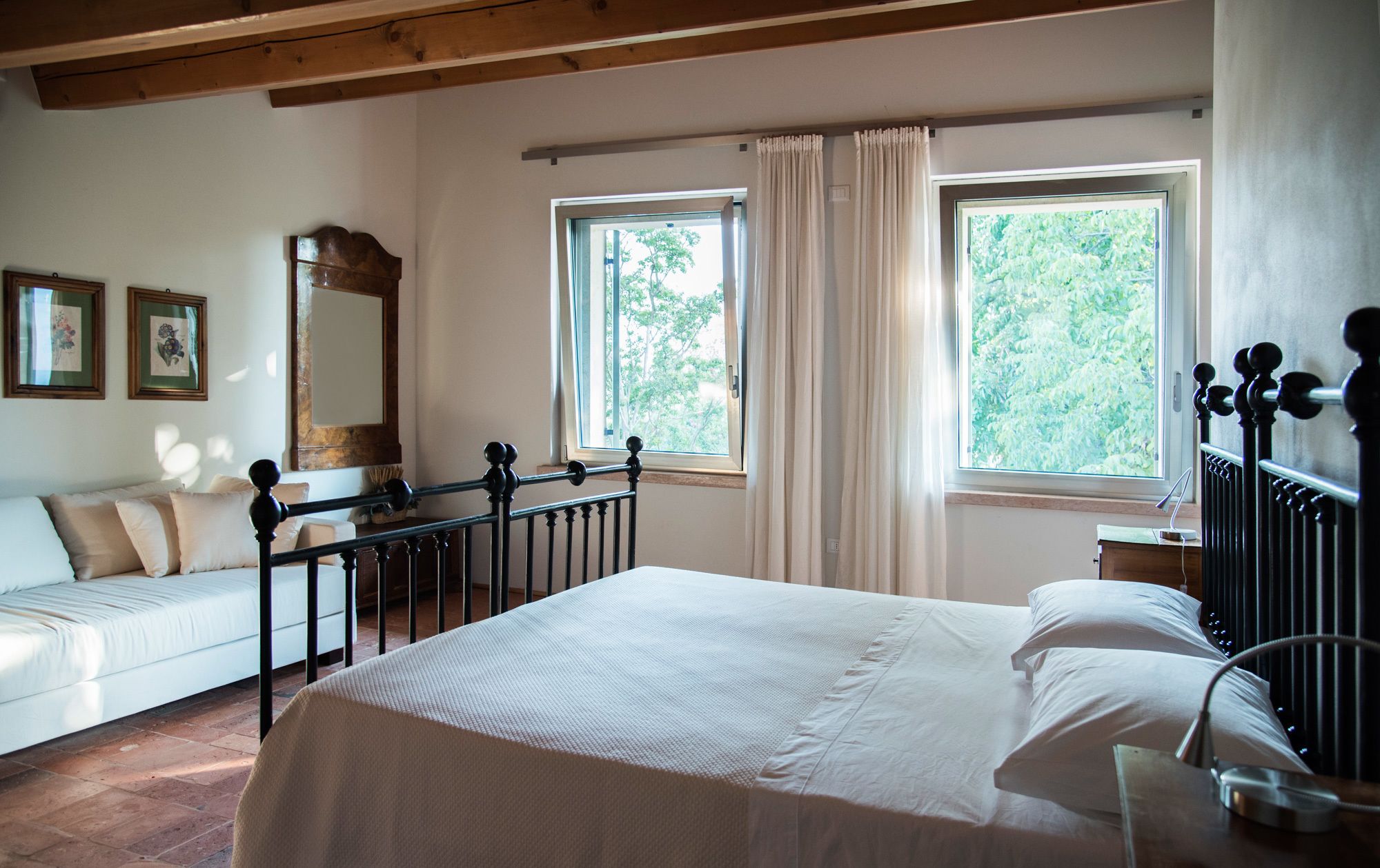 A bedroom with a bed, a window, a mirror, and a bedside table.