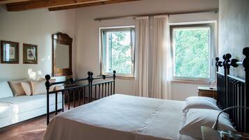 A bedroom with a bed, a window, a mirror, and a bedside table.