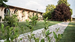 A building with arched windows and a garden with a gravel path. - Agriturismo Corte Ruffoni (Zevio)