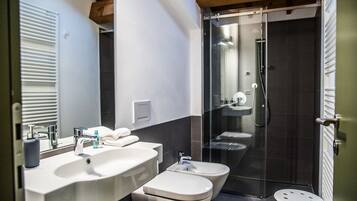Un baño moderno con lavamanos, inodoro, bidé y cabina de ducha con mampara de vidrio.