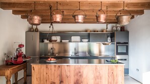 A modern kitchen with a wooden island, stainless steel appliances, and copper hanging pots. - Agriturismo Corte Ruffoni (Zevio)