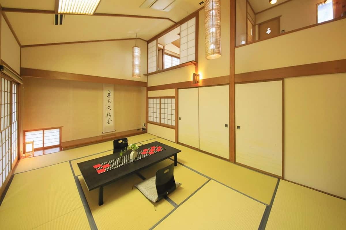 A traditional Japanese room with tatami flooring, a low table with a black mat, and sliding doors.