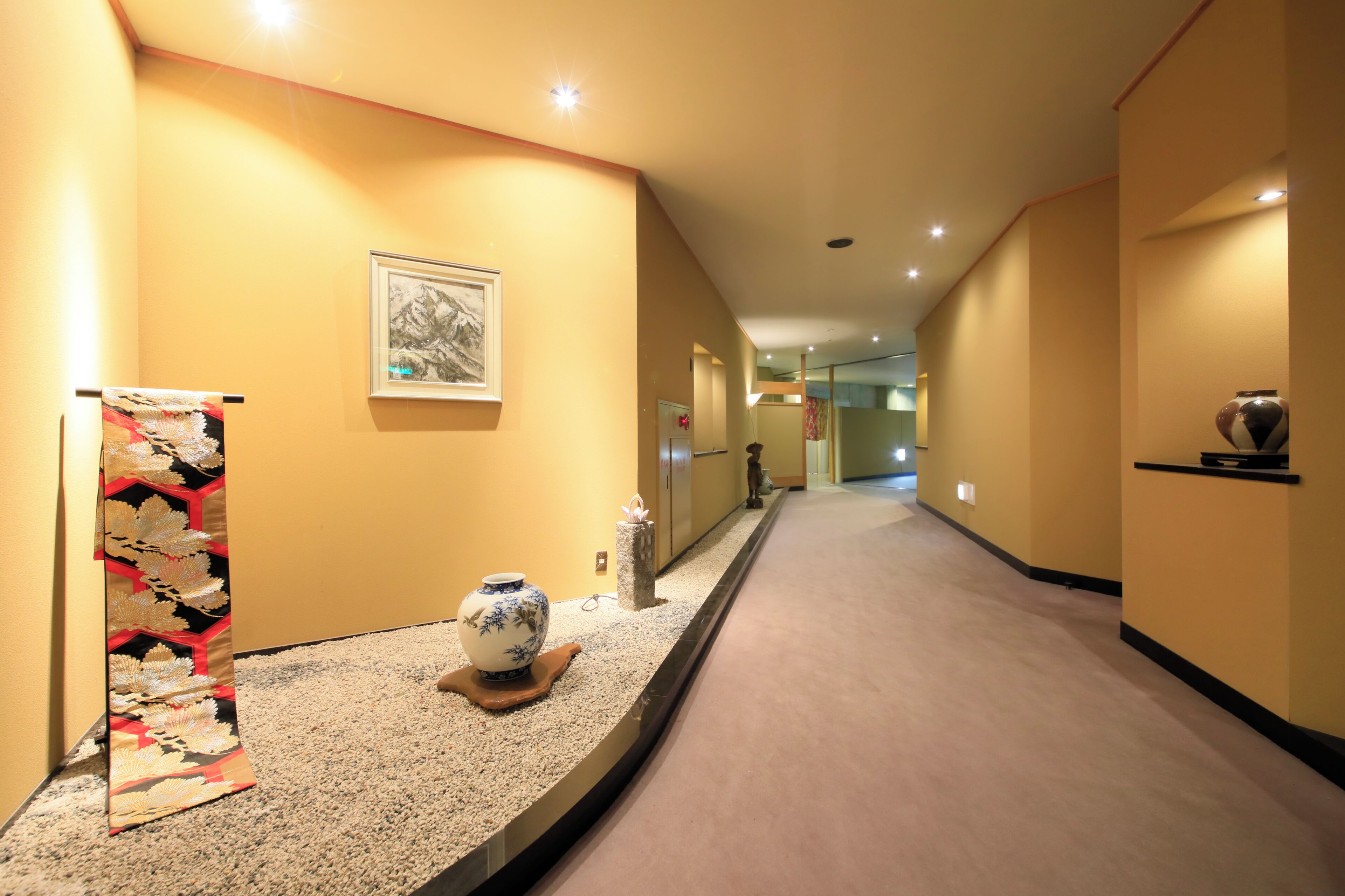 Un couloir orné d’un tapis décoratif, d’un vase et d’un tableau encadré accroché au mur.